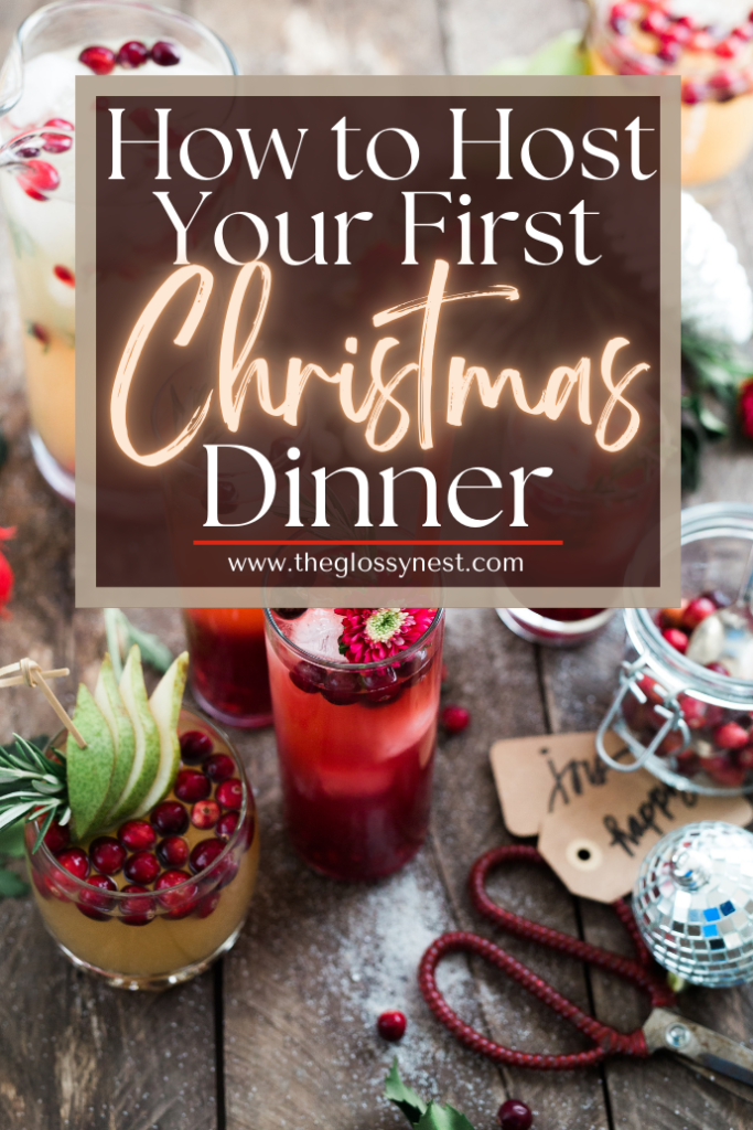 Festive drinks with pomegranate and rosemary are arranged on a wooden table. Text overlay reads, "How to Host Your First Christmas Dinner." Christmas ornaments and table settings add a holiday touch.