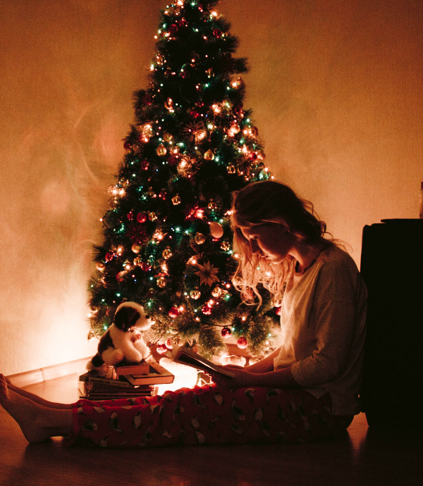 How to plan Christmas Day & Eve activities with girl sitting by Christmas tree