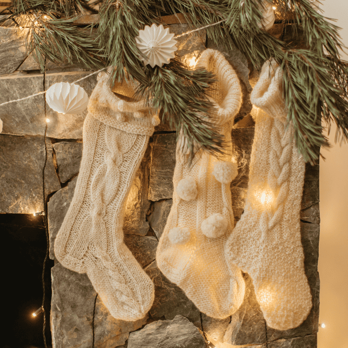 How to plan Christmas decorations with cream colored stockings, garland, greenery hung on a mantel