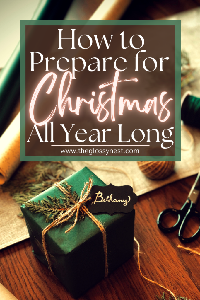 A beautifully wrapped green gift with a small branch tied to it sits on a table surrounded by string, scissors, and wrapping paper. A sign above reads "How to Prepare for Christmas All Year Long" with a website URL below.