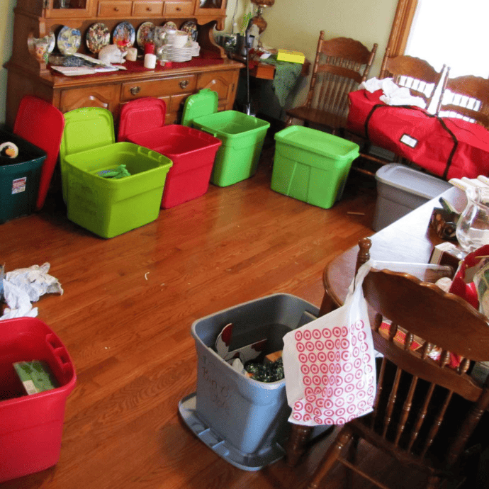 Putting Christmas decorations into storage bins in a dining room
