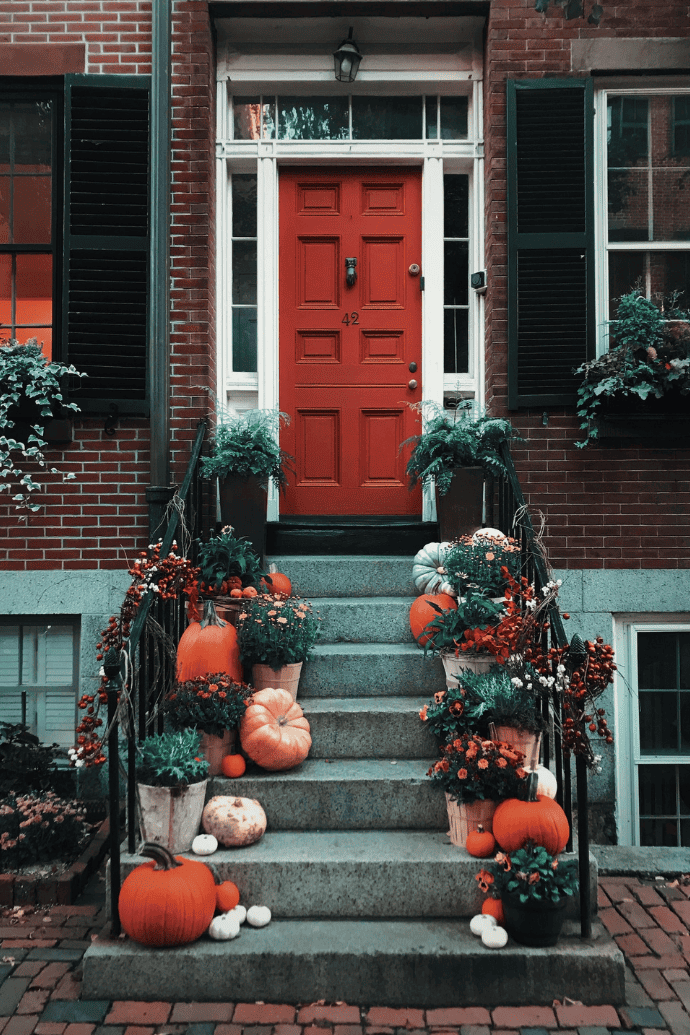 Front steps decorated for fall with pumpkins, mums