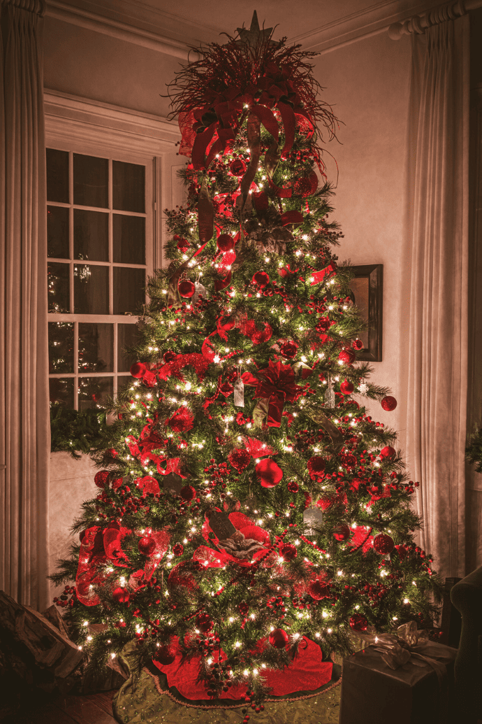 christmas tree at night with red ornaments, tree skirt