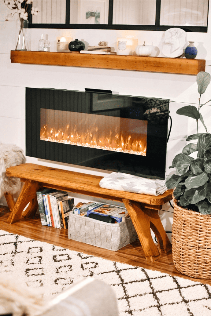 electric fireplace on wall with mantel, bench