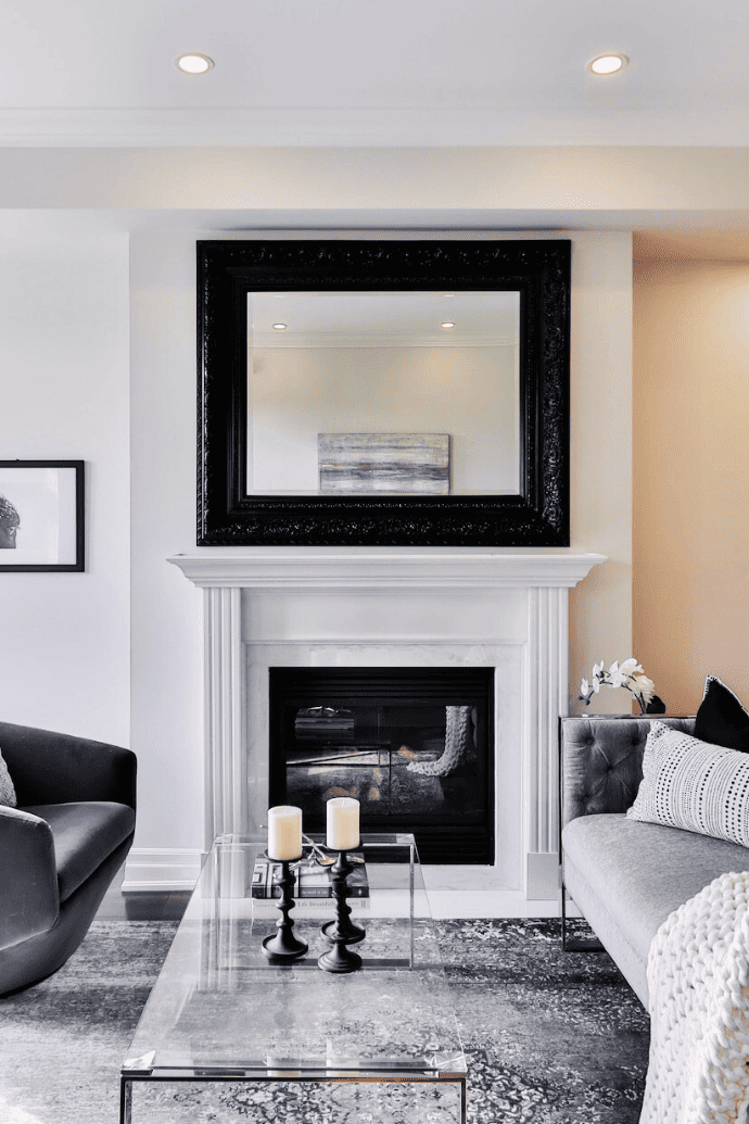 large black framed mirror above a white fireplace mantel