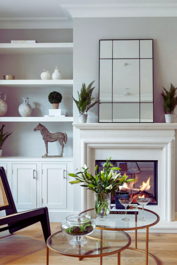 fireplace in living room with mirror, mantel, built ins, plants