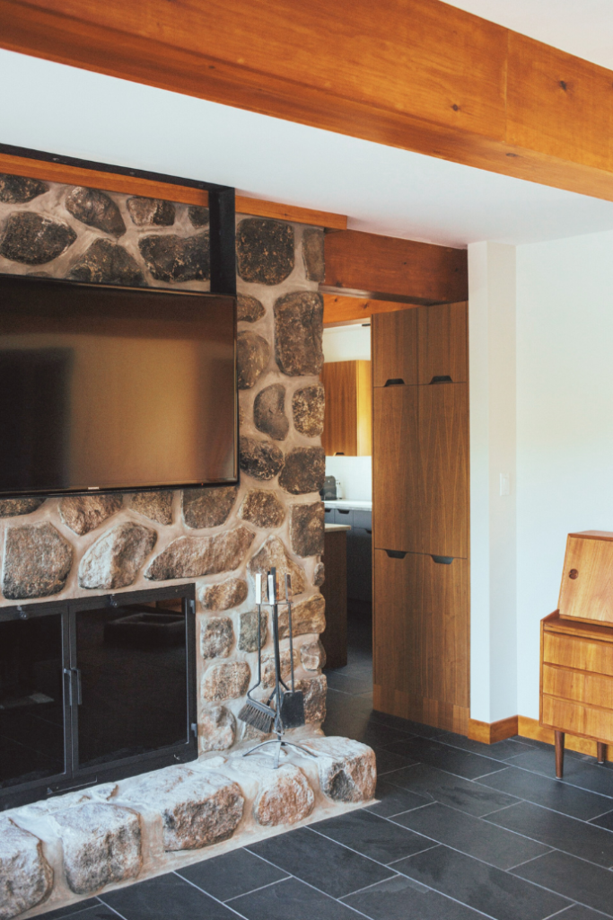 stone fireplace in basement with tv mounted above it