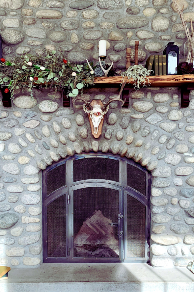 stone fireplace with mantel, books, skull, greenery, lanterns