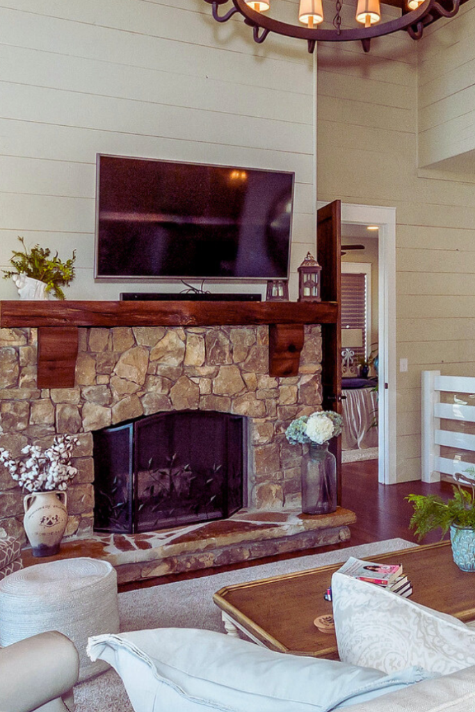fireplace with tv and sound bar mounted above it in living room with vases, plants, lanterns