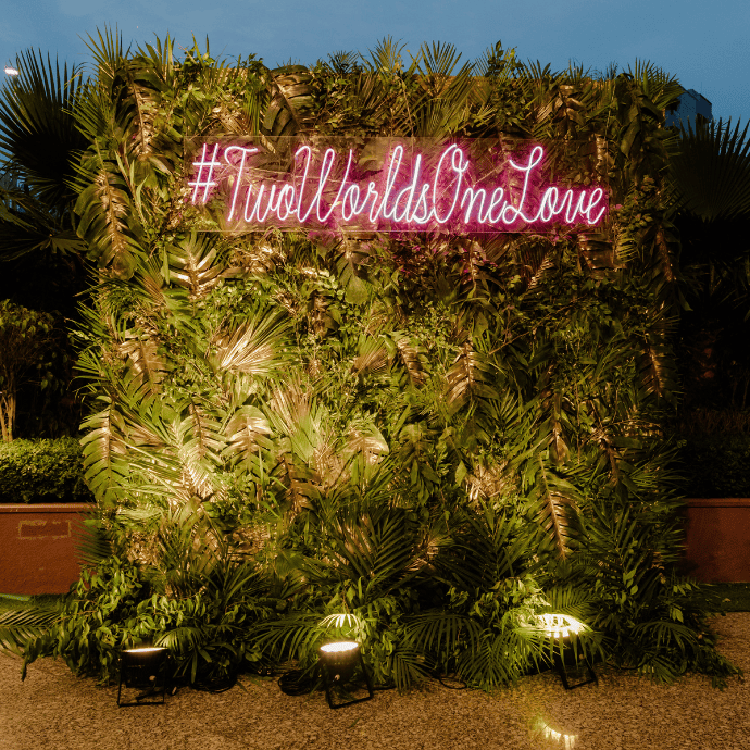 two worlds one love wedding neon sign with greenery wall backdrop