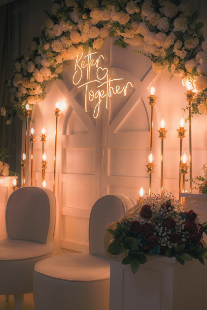 better together wedding neon sign on wood backdrop with flowers, lights, chairs