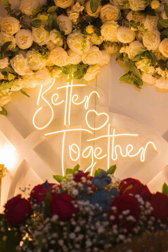 better together wedding neon sign on wood backdrop with florals