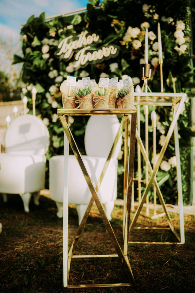 together forever wedding neon sign on greenery backdrop with florals, chairs, favors