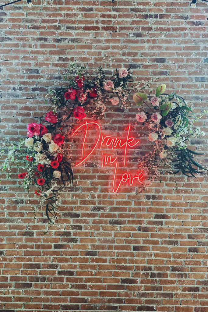 drunk in love neon sign for wedding with flowers, brick wall