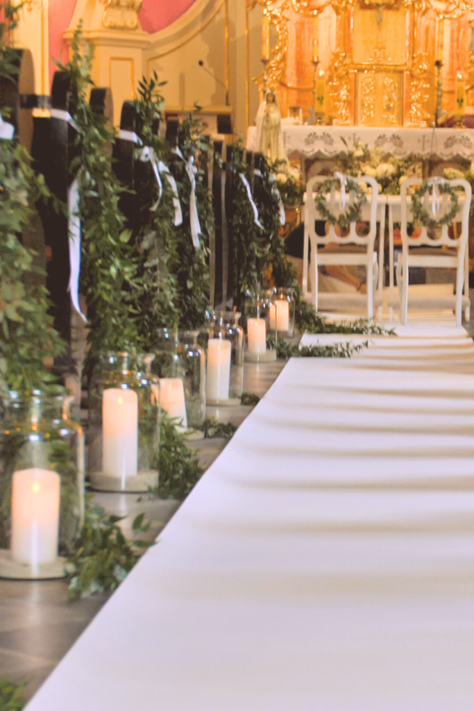 flameless candles in hurricanes, greenery, wedding aisle in church