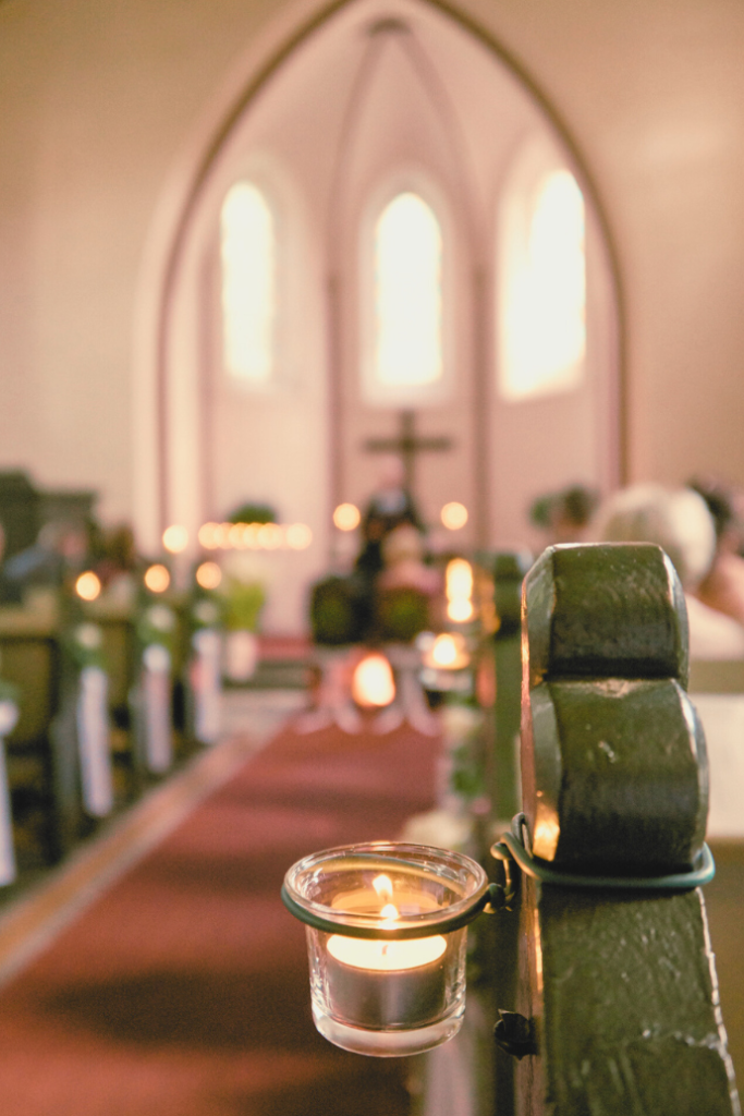 tealight candles on church pews down wedding aisle