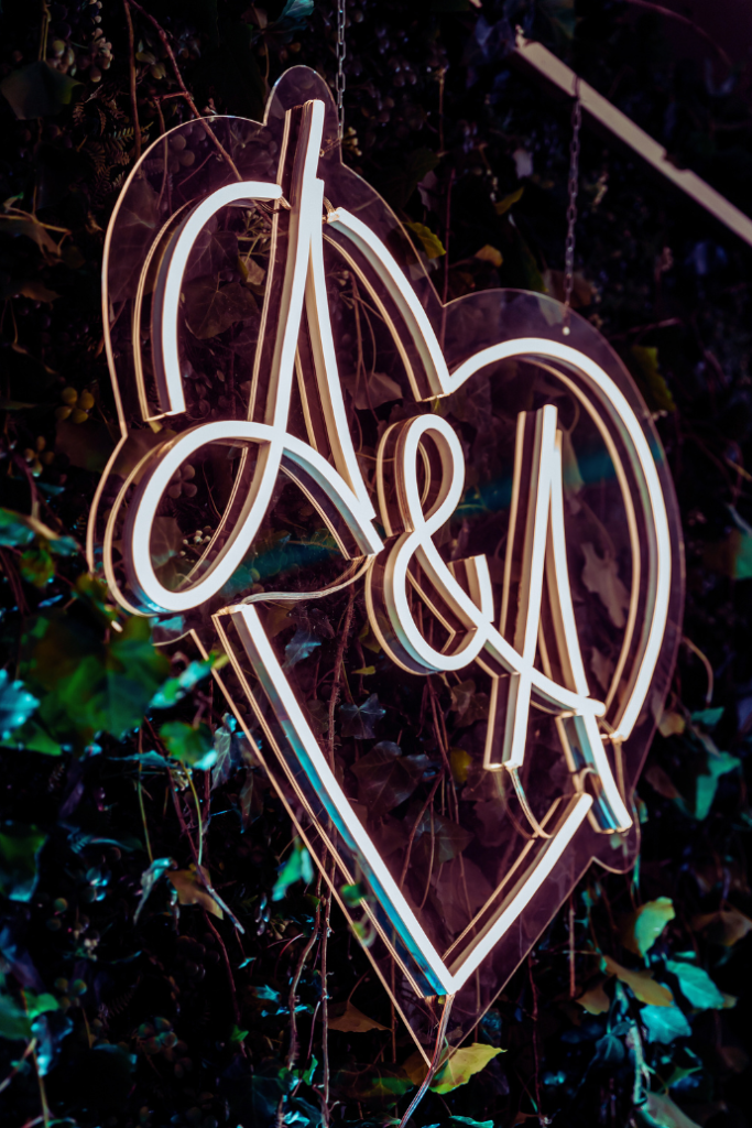 a & a wedding neon sign with initials on greenery backdrop, in heart shape, hanging