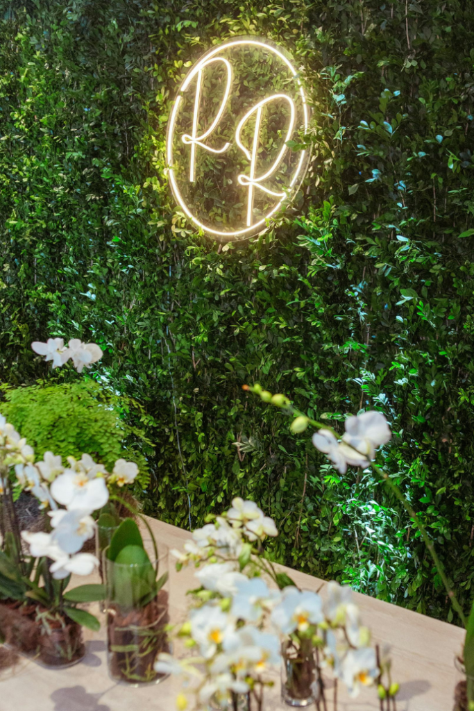 r & r wedding initials neon sign on greenery backdrop with flowers on table