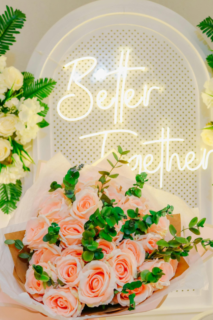 better together wedding neon sign on wood arch backdrop with flowers