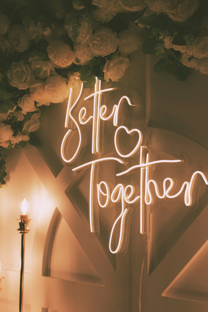 better together wedding neon sign on wood backdrop with flowers