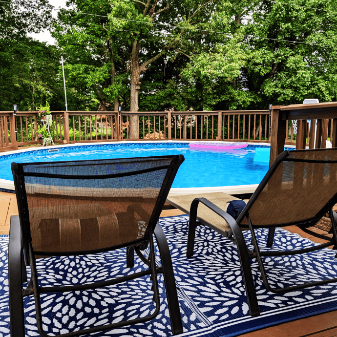 above ground pool with deck, chaise lounge chairs, rug