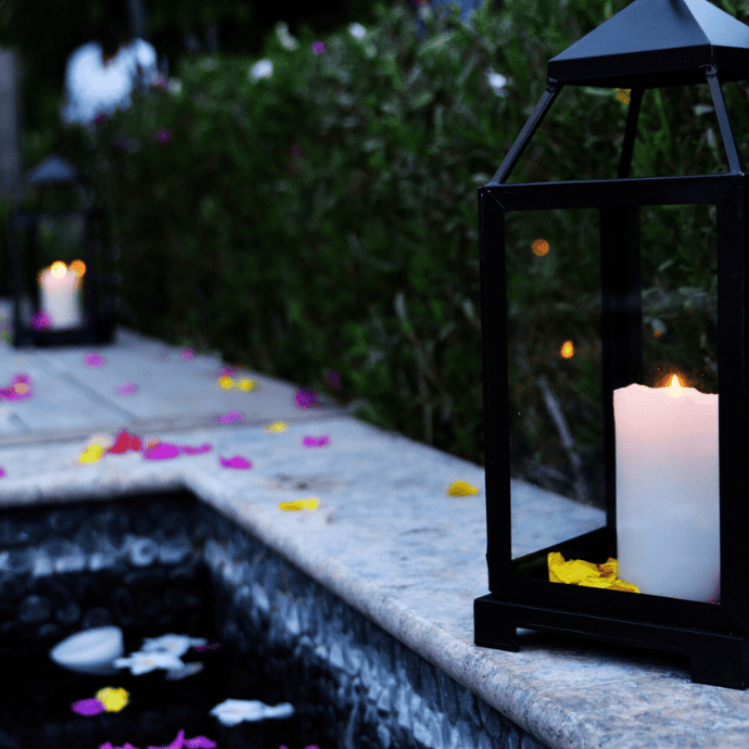 inground pool with lanterns, candles, flower petals at night
