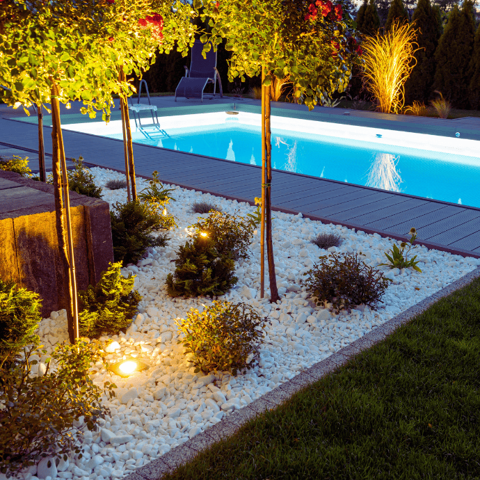inground pool with landscaping at night
