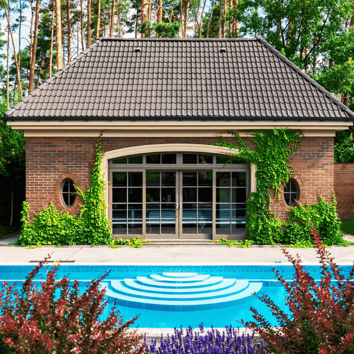 pool house with landscaping next to inground pool