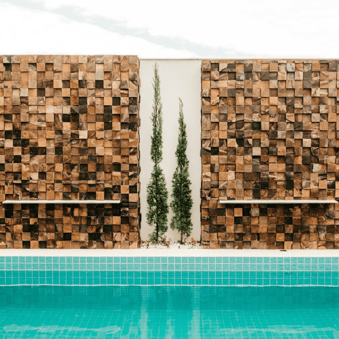 decorative wall beside inground pool with landscaping