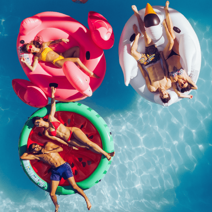 people hanging out in a pool on large pool floats