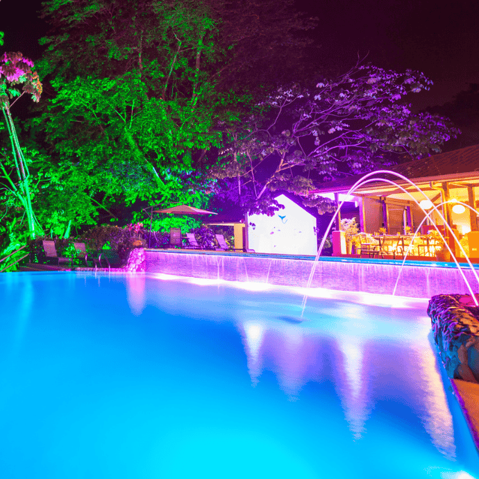 colorful lights surround a pool at night