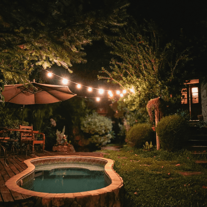 small backyard pool with string lights at night