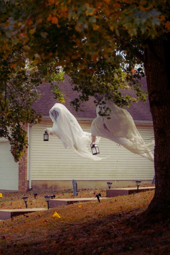 creepy ghosts with lanterns in front yard hanging from tree