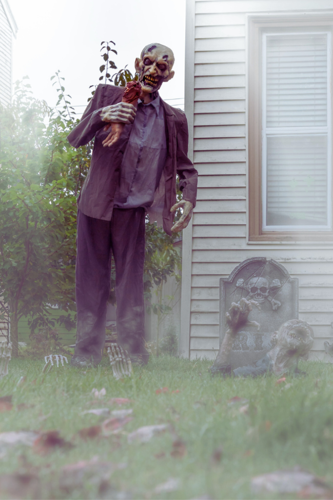 zombie man standing near house with bloody arm, gravestone