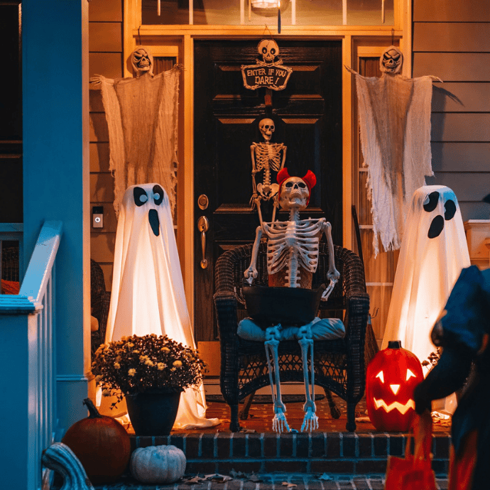 halloween front porch decorated with ghosts, skeletons, mum, jack-o-lantern