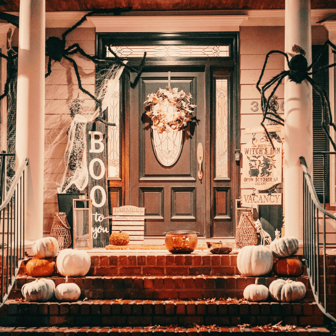 halloween front porch with spiders, pumpkins, boo sign, treat or treat candy bowl