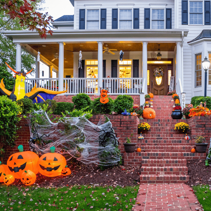 halloween front porch and yard with blow up decorations, pumpkins, mums, welcome sign