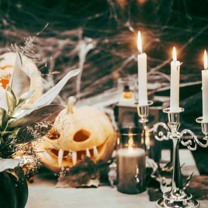 taper candles on table with halloween decorations, jack o lanterns