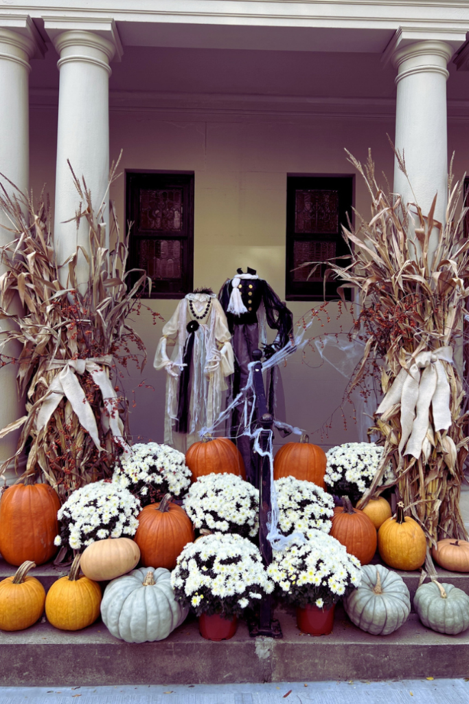 halloween headless couple props with fall pumpkins, mums, corn stalks on front porch