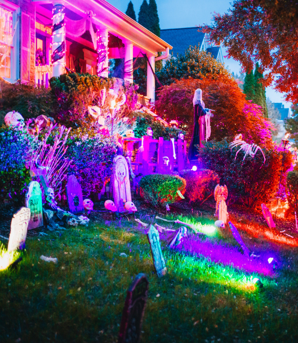 different colored up lights on halloween decorations in front yard