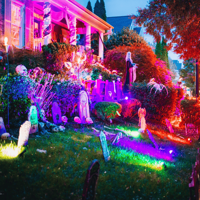 different colored up lights on halloween decorations in front yard