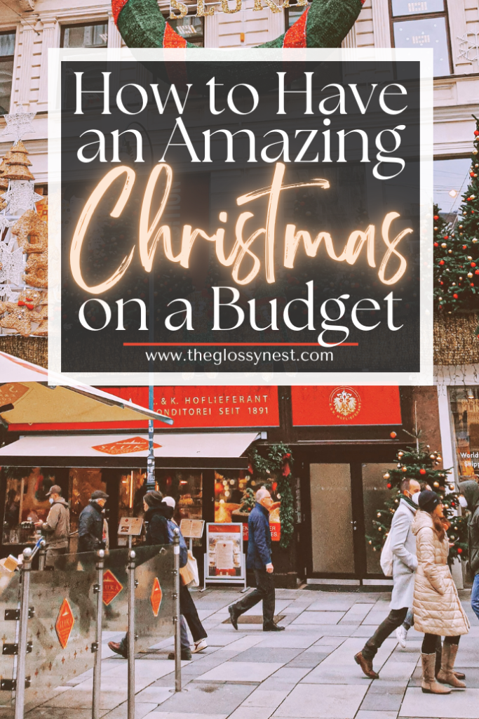 A festive street scene unfolds with a large holiday wreath, charmingly decorated shopfronts, and cheerful passersby. A sign invites, "Christmas Budget Planning: How to Have an Amazing Christmas On a Budget," complete with a handy website link below.