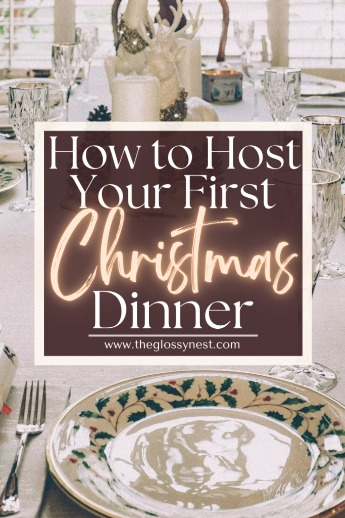 A festive dining table set for Christmas, adorned with elegant glassware and decorative plates. A candle centerpiece and a framed title reading "How to Host Your First Christmas Dinner" with the website "www.theglossynest.com" are visible.