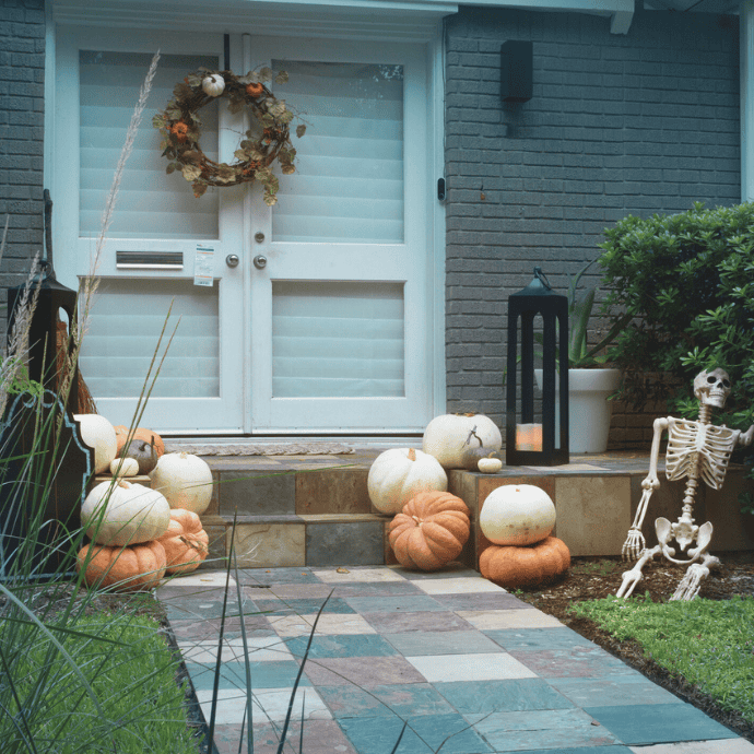 farmhouse halloween front porch decorations with pumpkins, lantern, skeleton, wreath