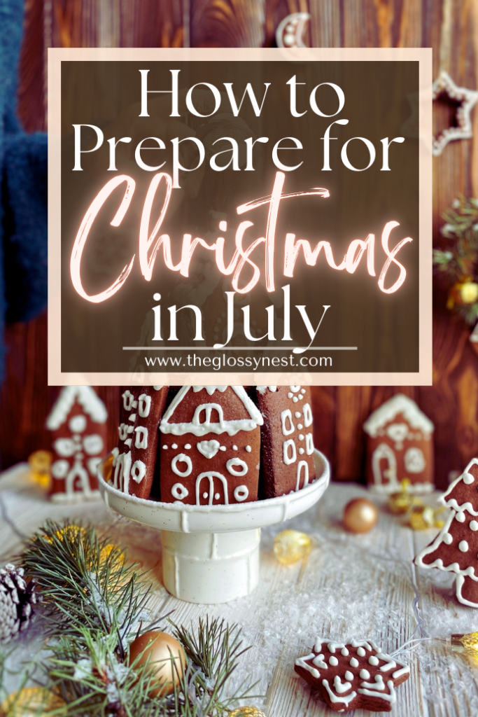 A festive setup with gingerbread houses on a cake stand surrounded by pine branches and ornaments. Text overlay reads: "How to Prepare for Christmas in July. www.theglossynest.com"