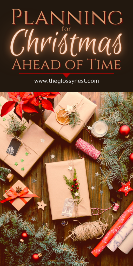 Festive flat lay with wrapped gifts, pine branches, red ornaments, and a candle on a wooden table. Text at the top reads, "Planning for Christmas Ahead of Time" with a website URL www.theglossynest.com.